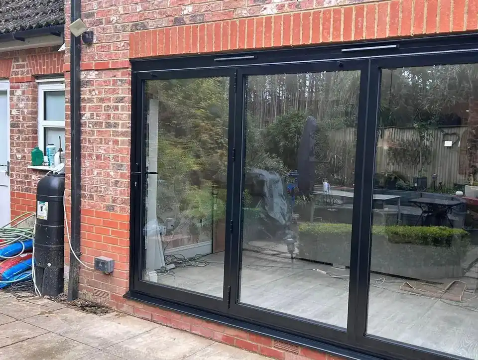 Black aluminium bifold doors fitted in a red brick extension